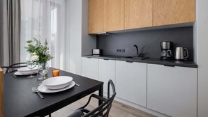 Une cuisine moderne avec des meubles en bois, un plan de travail noir et un coin repas avec une table dressée pour deux personnes.