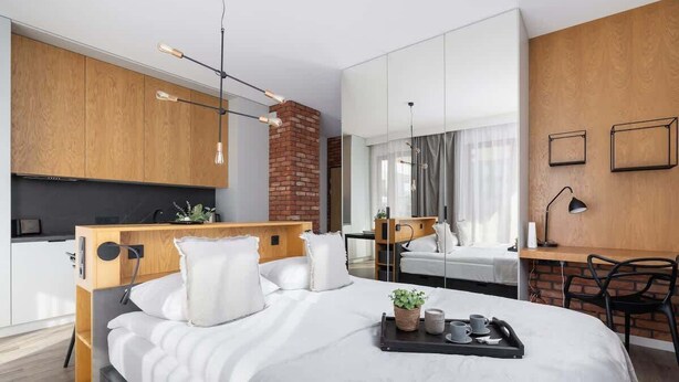 Une chambre d’hôtel moderne équipée d’un lit, d’une table de chevet et d’un espace bureau.