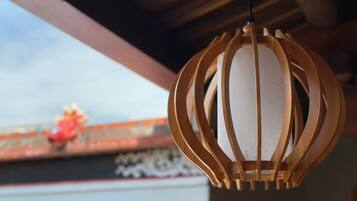 Um lanterna de madeira pendurada, com interior branco, suspensa por uma estrutura de vigas de madeira.