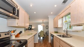 A modern kitchen with wooden cabinets, a built-in oven, and a dishwasher. - Tybee Paradise Beach House for Families, Pet Friendly (Tybee Island)