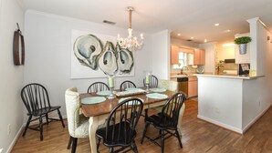 A dining area with a wooden table, black chairs, and a chandelier. - Tybee Paradise Beach House for Families, Pet Friendly (Tybee Island)