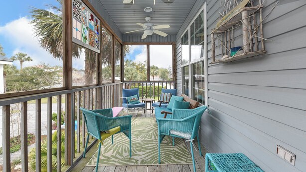 A covered porch with wicker furniture, a ceiling fan, and a view of the outdoors. - Tybee Paradise Beach House for Families, Pet Friendly (Tybee Island)