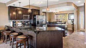 A modern kitchen with dark wood cabinets, stainless steel appliances, and a central island with bar stools. - Branson Getaway • Sunroom + Balcony + Stunning Table Rock Lake View (Branson)