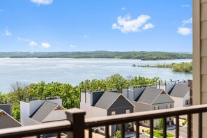 A residential area with houses overlooking a large body of water and a distant hill.