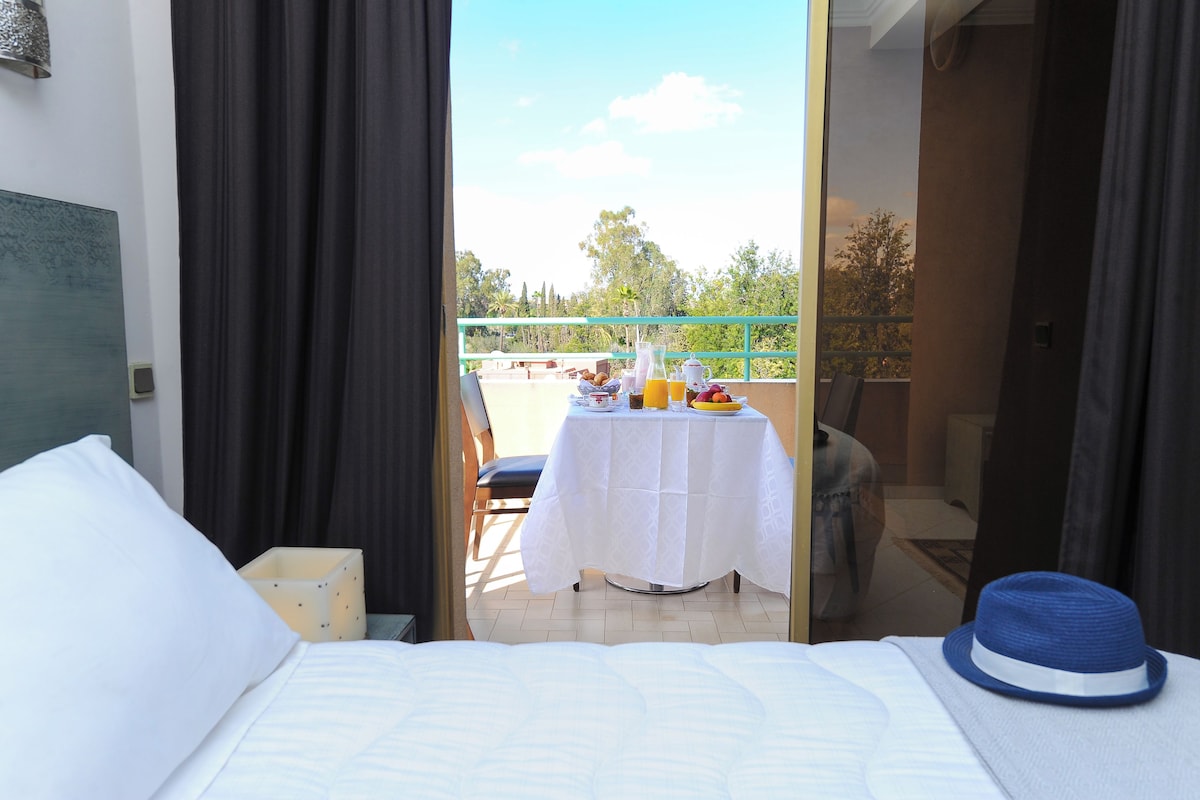 Une chambre d’hôtel avec un lit, une table où sont servis les articles du petit-déjeuner et une vue sur l’extérieur.