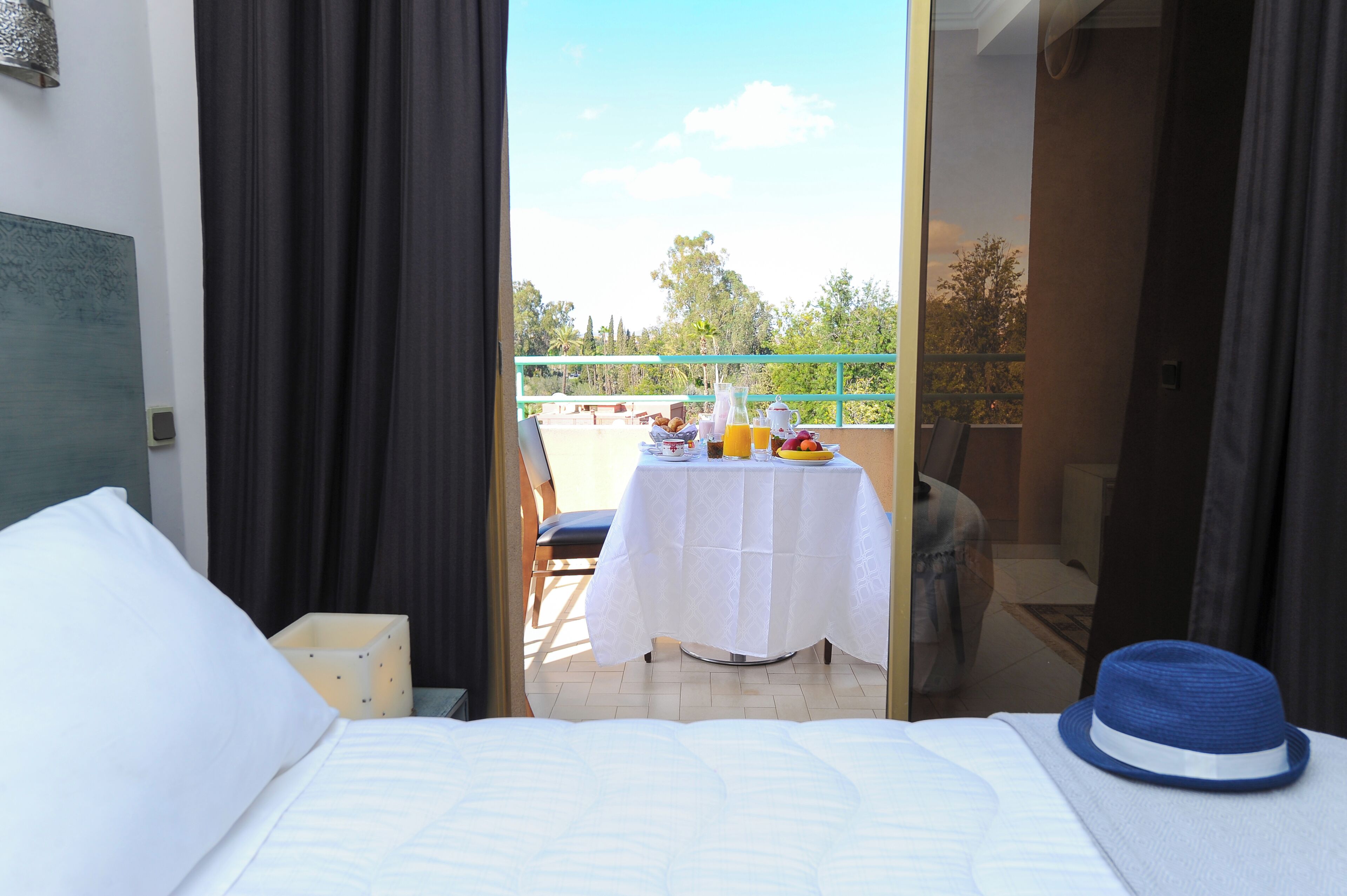 A hotel room with a bed, a table with breakfast items, and a view of the outdoors.