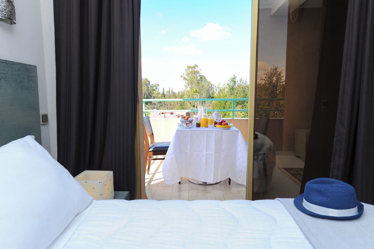 A hotel room with a bed, a table with breakfast items, and a view of the outdoors.