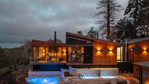 Una casa moderna con piscina, mobiliario exterior y un patio de piedra.