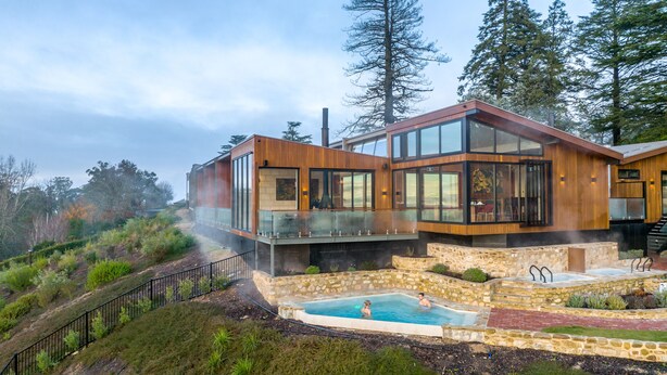 Una casa moderna con piscina, rodeada de árboles y una terraza de piedra.