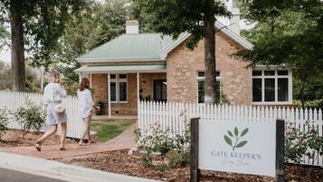 A stone building with a green roof and a white picket fence. A sign in front reads "GATE KEEPER'S Dog Spa".