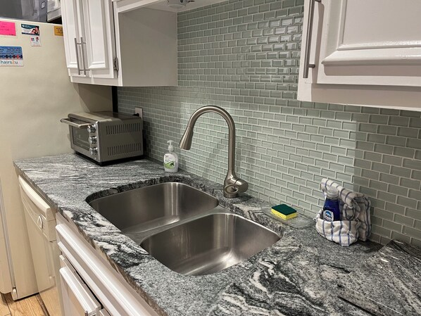 A kitchen with a double stainless steel sink, a toaster, and a dish soap bottle on the counter.