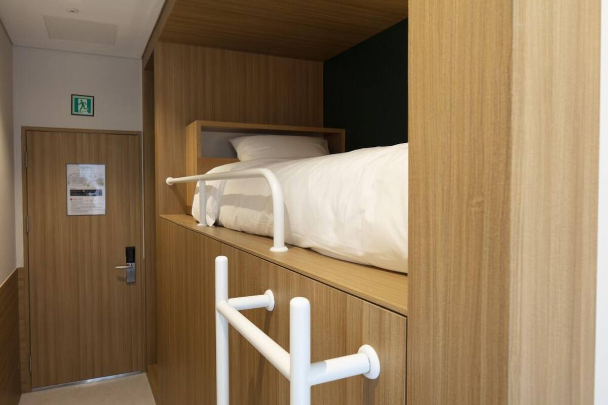 A bunk bed with a wooden headboard and white bedding.