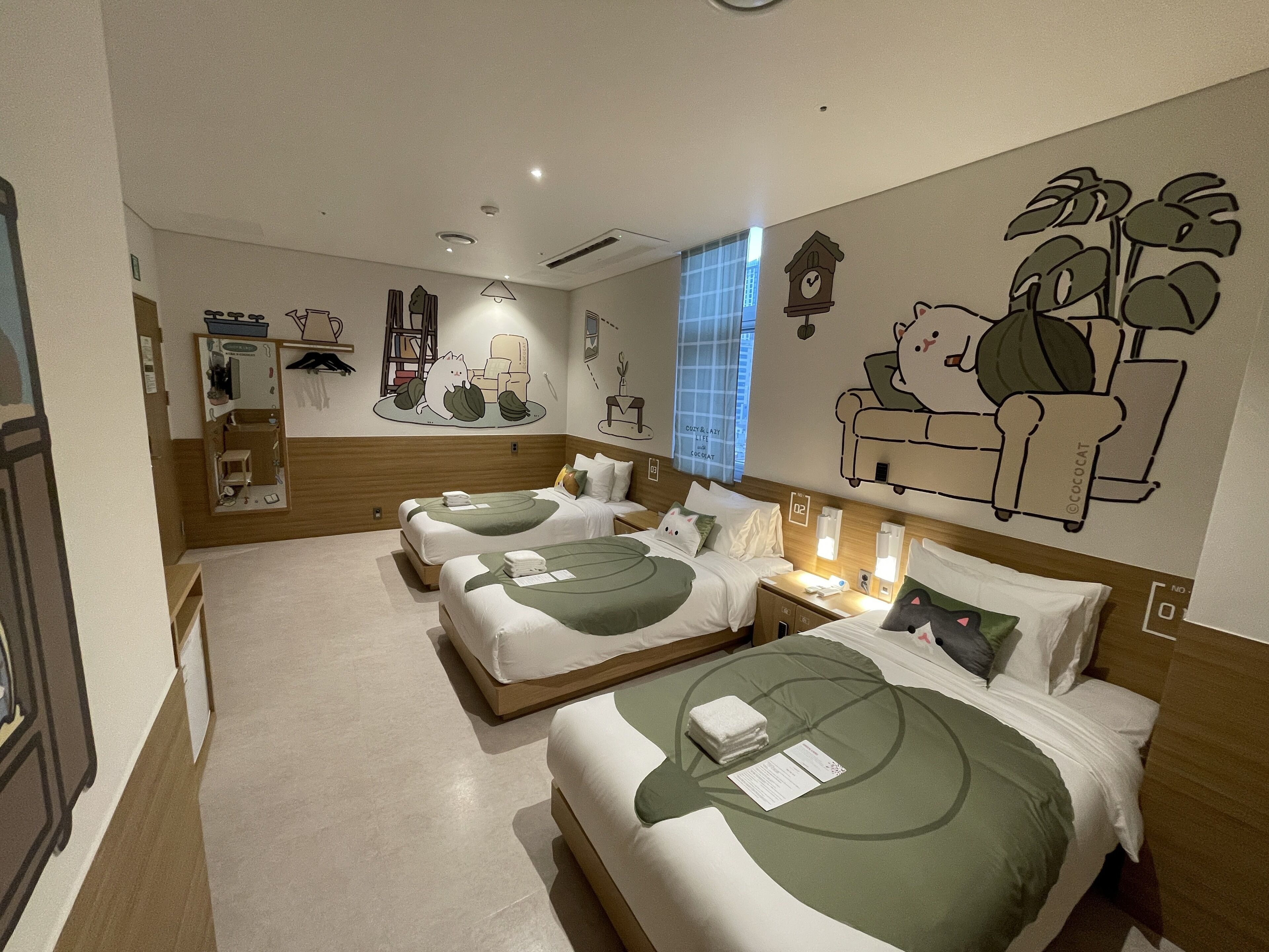 Habitación de hotel con dos camas, cabecero de madera, un reloj de pared y una ventana con persianas.