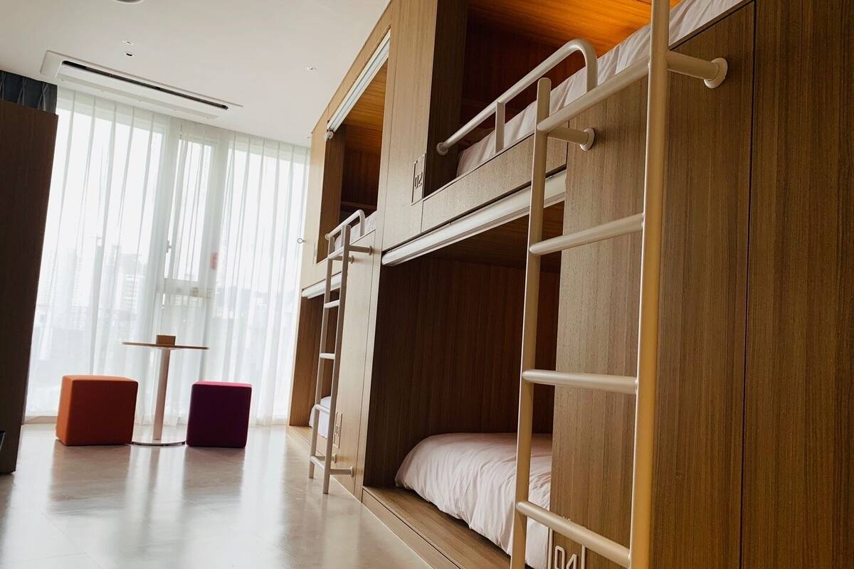 A bunk bed room with a ladder, a small table, and two chairs.