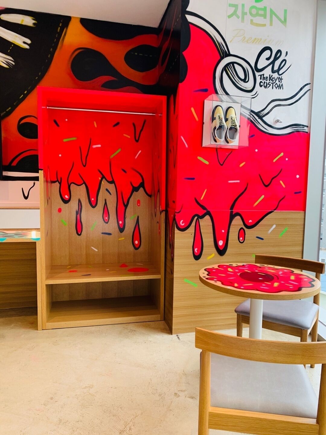 Una habitación con un mural llamativo, un mueble de madera y una pequeña mesa con una silla.