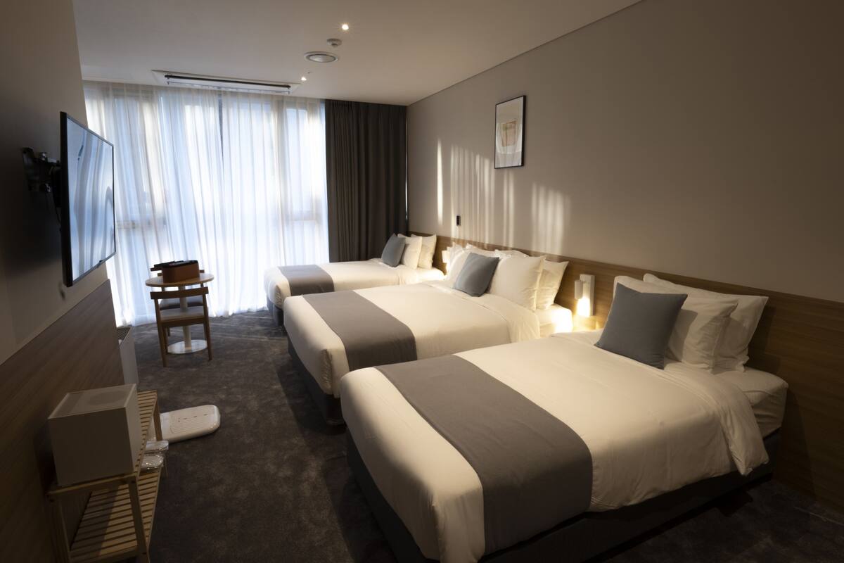 A hotel room with two beds, a TV, a desk, and a chair.