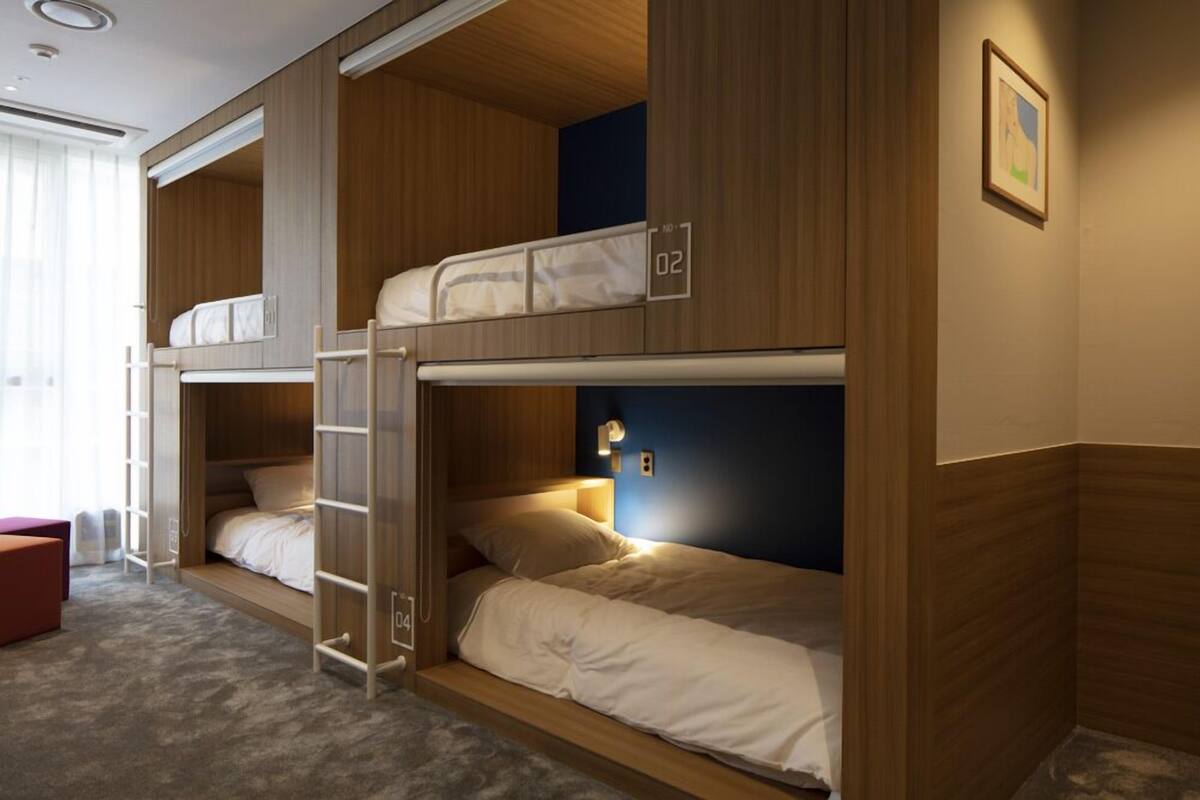 A bunk room with two beds, a ladder, and a small seating area.