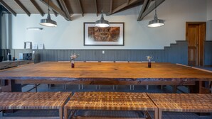 A large wooden conference table with benches, pendant lighting, and a framed picture of a lion on the wall.