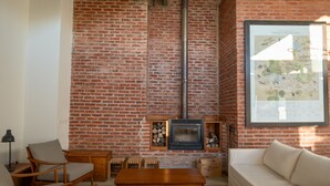 A living room with a brick wall, wooden furniture, a fireplace, and a framed map.