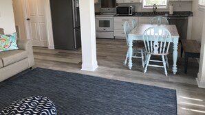 Eine moderne Küche mit weißen Schränken, einem Edelstahl-Kühlschrank, einer Mikrowelle und einem Esstisch mit Stühlen.