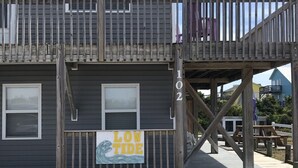 Ein zweistöckiges Gebäude mit Holzterrasse und einem Schild mit der Aufschrift 'LOW TIDE'.
