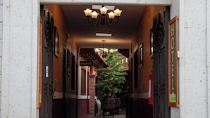L’entrée d’un hôtel, avec le numéro « 67 » au-dessus de la porte, un comptoir d’accueil et un lustre.