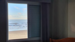A room with a large window overlooking a beach. - Beachfront apartment with a privileged ocean view. (SP)