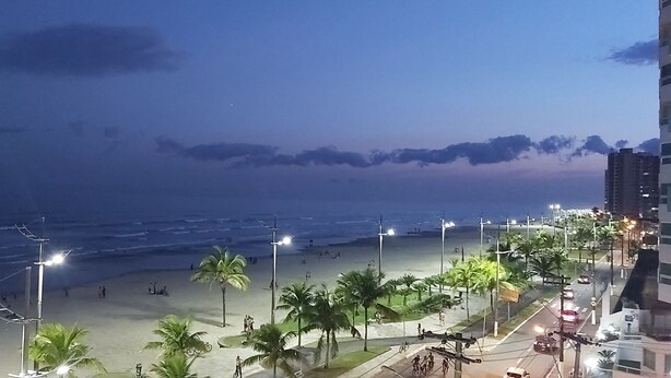 A beach with people, palm trees, and streetlights. - Beachfront apartment with a privileged ocean view. (SP)