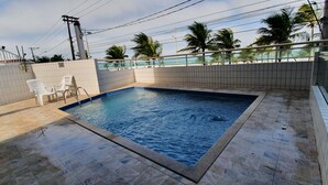 A rectangular swimming pool with tiled edges, surrounded by a tiled deck area. - Beachfront apartment with a privileged ocean view. (SP)
