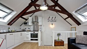 A modern kitchen with white cabinets, a stainless steel range hood, and a built-in microwave. There is a wooden ceiling with exposed beams, and a skylight above the sink. - Free Parking - Free Wi-Fi - 2km From The Beach (Strete)