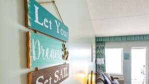 Un salon comprenant un canapé, une lampe et des éléments de décoration murale, notamment des panneaux sur lesquels on peut lire : « Laissez vos rêves prendre leur envol. »