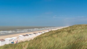 A beach with white beach huts and a grassy dune. - Calista 213 with balcony by Interhome (Bredene)