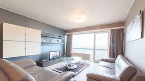 A modern living room with two leather sofas, a glass coffee table, and a flat-screen TV on a stand. - Calista 213 with balcony by Interhome (Bredene)