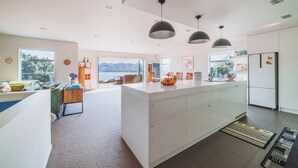 Een moderne keuken met een centraal eiland, hanglampen en uitzicht op de omgeving.