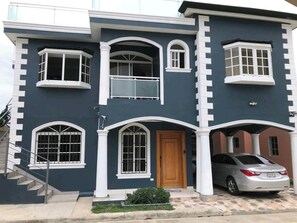 A two-story house with a garage, a staircase, and a car parked in the driveway.