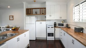 Una cocina moderna con armarios blancos, encimera de madera, horno integrado, microondas y estufa.