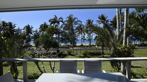 An outdoor seating area with a view of the beach and palm trees. - Ohana - Beachfront Holiday House (South Mission Beach)