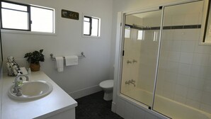 A bathroom with a glass-enclosed shower, a sink, a toilet, and a potted plant. - Ohana - Beachfront Holiday House (South Mission Beach)