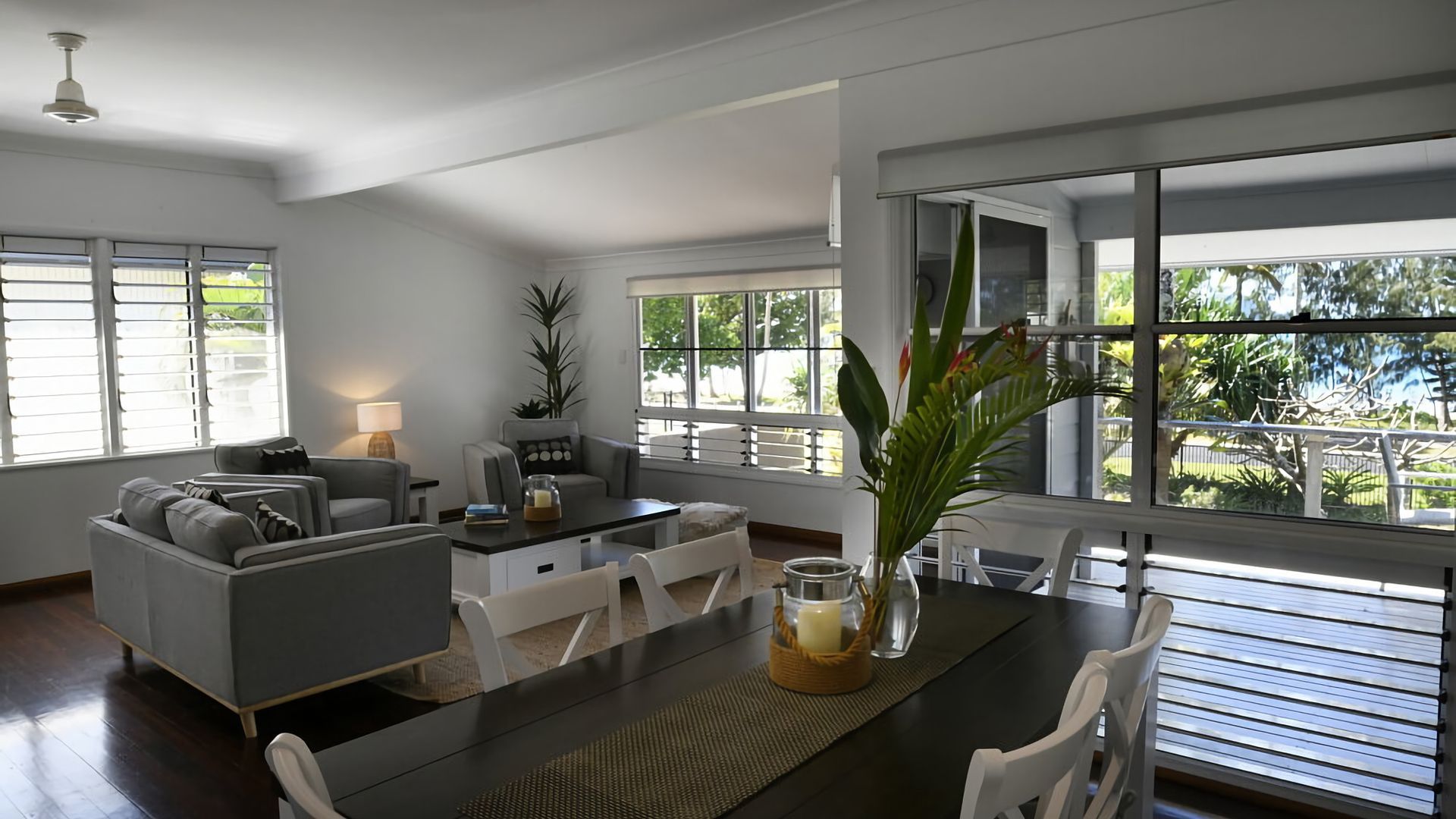 Un salon moderne avec un coin repas, de grandes fenêtres et une vue sur la verdure.