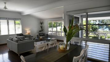 Un salon moderne avec un coin repas, de grandes fenêtres et une vue sur la verdure.