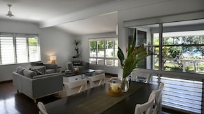 Un salon moderne avec un coin repas, de grandes fenêtres et une vue sur la verdure.