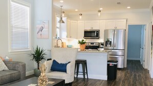 A modern kitchen with white cabinets, stainless steel appliances, and pendant lighting. - Yellow Door Cottage In The Heart of Bay St. Louis (Bay St. Louis)