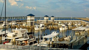 A marina with multiple boats docked, a pier extending into the water, and a bridge in the background. - Yellow Door Cottage In The Heart of Bay St. Louis (Bay St. Louis)