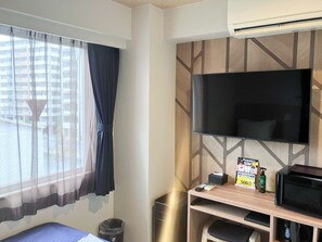 A hotel room with a bed, a TV mounted on the wall, a small table with a remote control, a trash bin, and a window with curtains. - Hotel Livemax Naha-matsuyama (Naha)