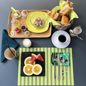 Ein Frühstücksangebot mit Gebäck, Marmeladen und einer Tasse Kaffee auf einer Holzbrett.