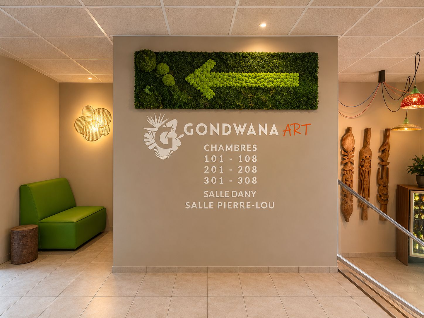Een ontvangstruimte met een groene bank, een kunstwerk aan de muur en een trap met houten sculpturen.