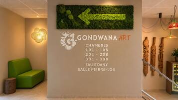Een ontvangstruimte met een groene bank, een kunstwerk aan de muur en een trap met houten sculpturen.