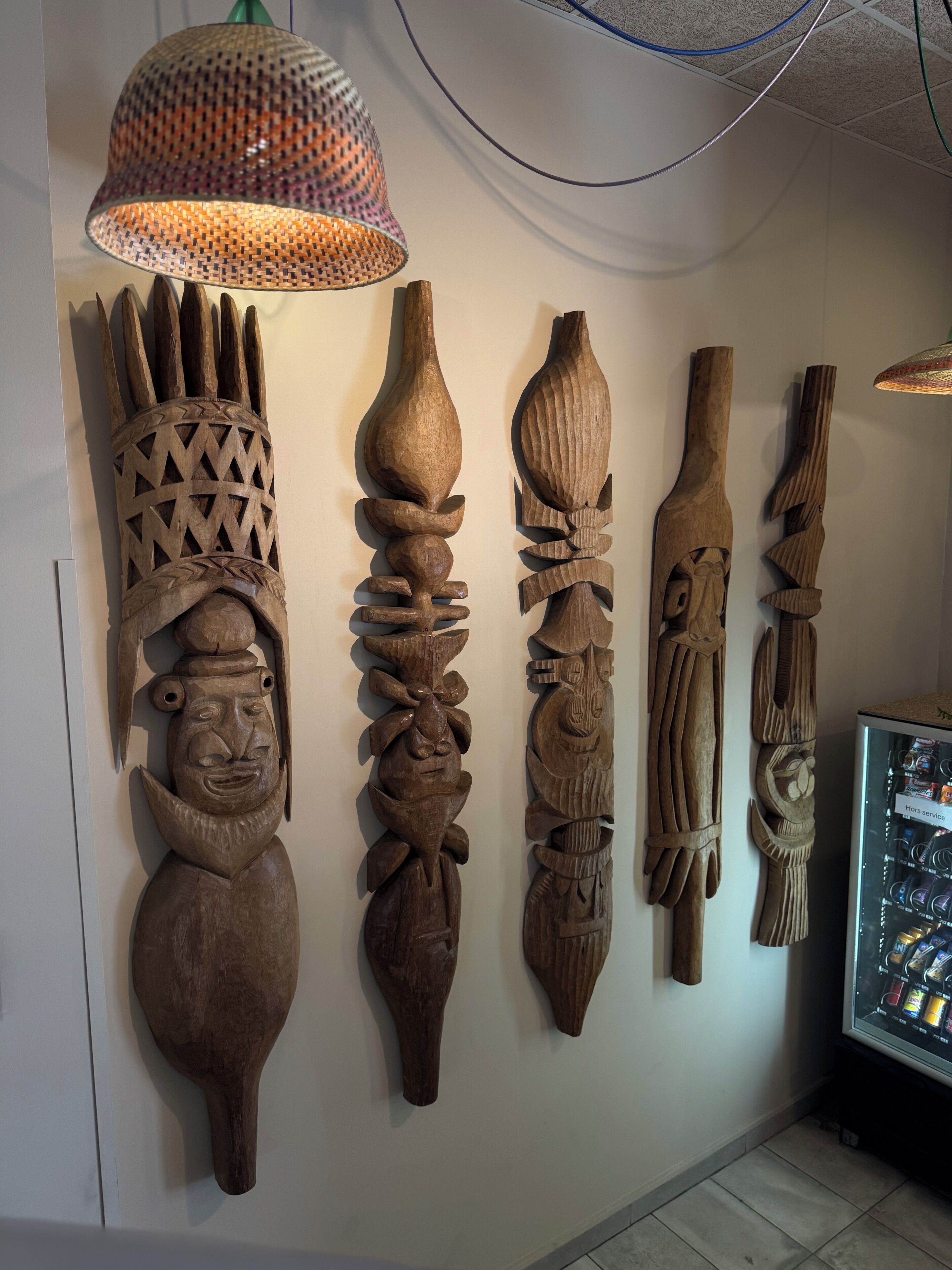 A wall with wooden carvings and a hanging lamp.