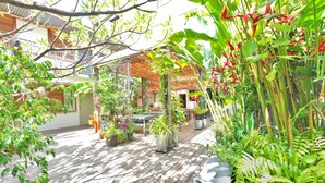 A wooden deck with potted plants and a building in the background. - Hôtel Gondwana - City ART (Nouméa)