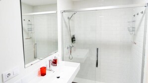 Un bagno moderno con un lavandino bianco, uno specchio grande e una cabina doccia in vetro.